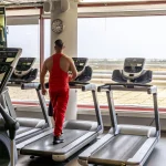 Interior do ginásio com clientes a usar máquinas de exercício e pesos